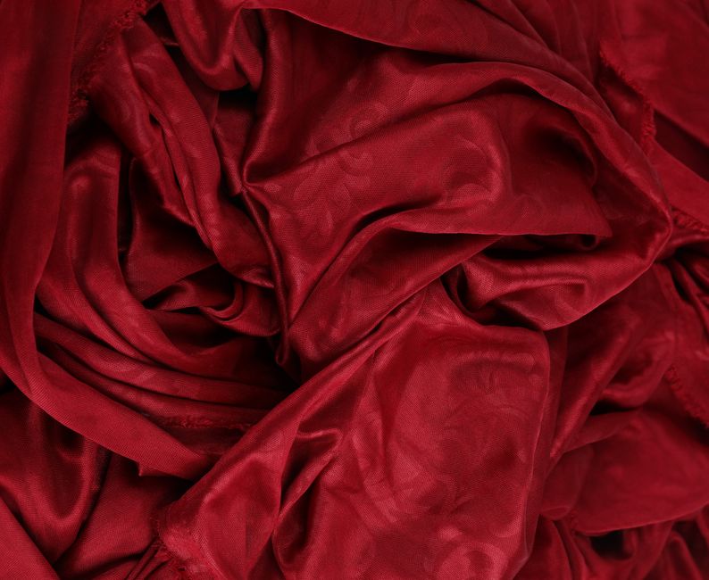 Close-up of luxurious red fabric with intricate texture and folds.